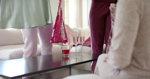 African american women gathering at home holding champagne flutes and sequined bag