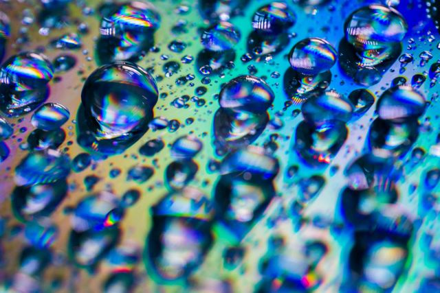 Colorful close-up water droplets creating beautiful abstract reflections. Ideal for artistic backgrounds, design inspirations, or illustrating concepts related to water, reflection, and light. Suitable for use in digital art projects, science illustrations, or as visually appealing decorative prints.