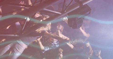 Hands reaching toward stage truss at neon club night, crowd pushing through haze and light