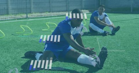Young soccer players stretching before training on turf with agility hurdles
