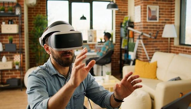Bearded man wearing vr headset reaching forward in modern loft office engaging virtual interface