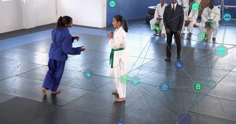 Young judo athletes sparring with referee and judges, digital tech network overlay