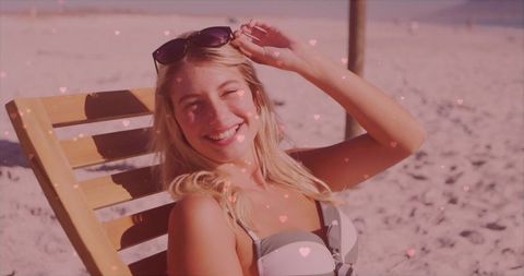 Woman relaxing on beach chair with sunglasses and hearts overlay