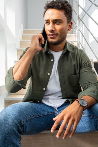 Man in Olive Shirt Using Smartphone While Sitting on Staircase