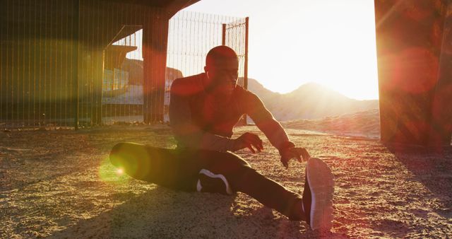 Athletic man is stretching outdoors at sunset with a scenic mountain background. Ideal for promoting fitness, outdoor exercise, healthy living, and athletic gear. Perfect for health blogs, sports advertisements, and fitness programs.