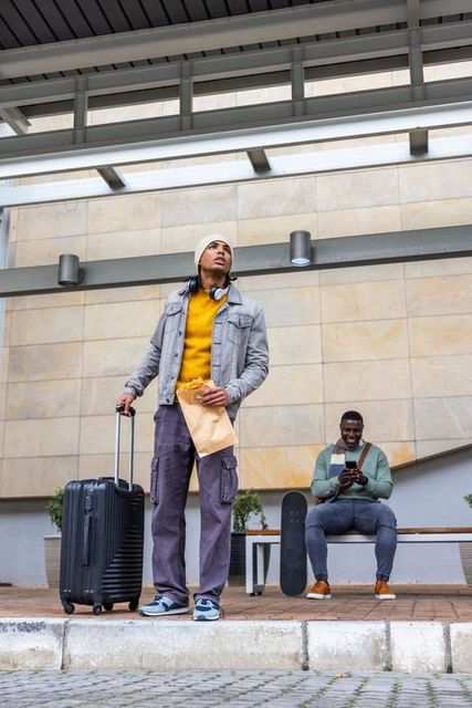 Young diverse commuters waiting with luggage and skateboard at modern transit platform