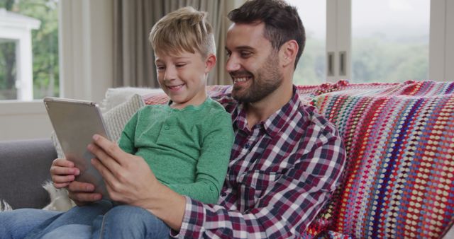 Father and Son Smiling While Reading from Tablet at Home - Download Free Stock Images Pikwizard.com