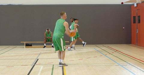 Diverse male basketball players passing cutting shooting and rebounding on indoor court