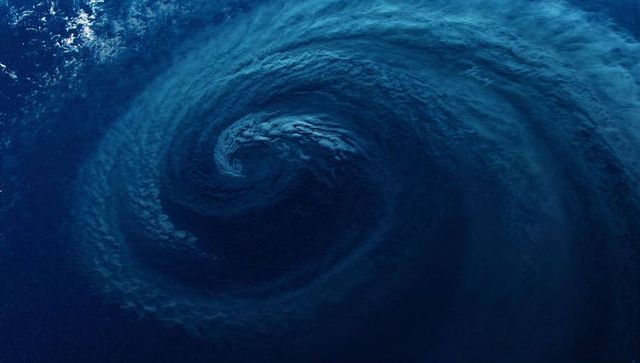 Dark blue ocean vortex spiraling water into whirlpool with foamy whitecaps
