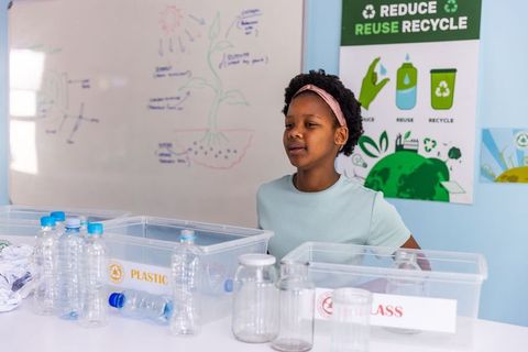 African american girl sorting recyclables in classroom teaching recycling sustainability