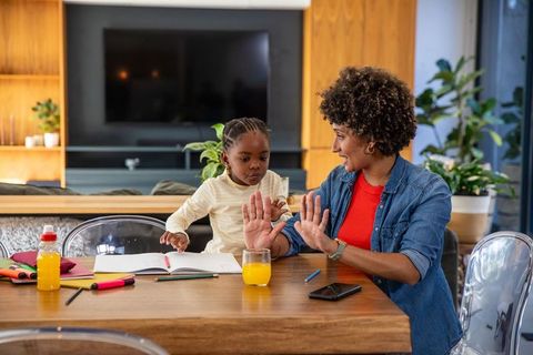 Mother Teaching Daughter Counting with Fingers at Kitchen Table