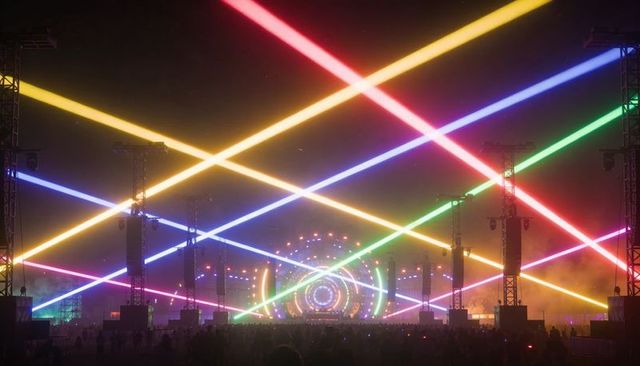 Neon laser spectacle at outdoor music festival featuring colorful beams, led stage, fog
