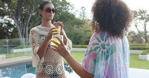 Poolside style: women wearing crochet coverup and sunglasses enjoying citrus drinks