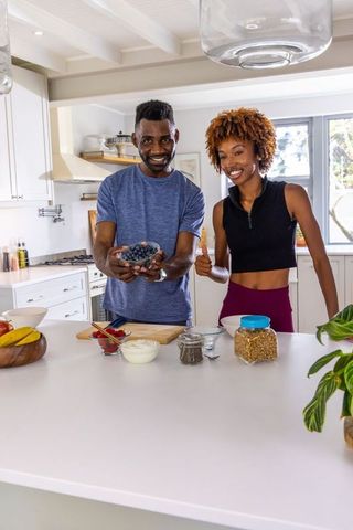 Couple preparing healthy breakfast with blueberries in bright modern kitchen