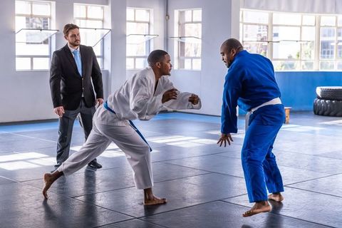 Referee Supervising Martial Arts Match on Blue Mats in Gym