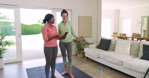 Diverse female friends practicing yoga following smartphone routine