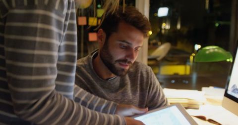 Young man intently working on tablet late at night