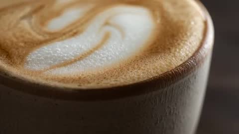 Macro coffee cup video focusing on heart latte art, creamy microfoam texture, ceramic rim