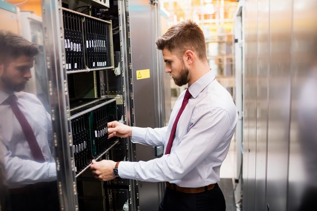 Technician examining server in data center, ensuring proper functionality and maintenance. Ideal for use in articles about IT infrastructure, technology services, network management, and professional workplace environments.