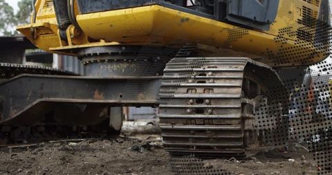 Yellow excavator tracks navigating construction site terrain