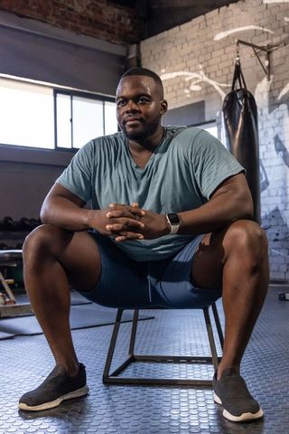 Focused athlete sitting on metal box resting between training rounds in industrial gym