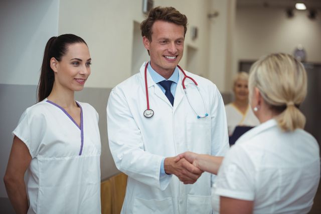 Doctor shaking hand with nurse in corridor at hospital