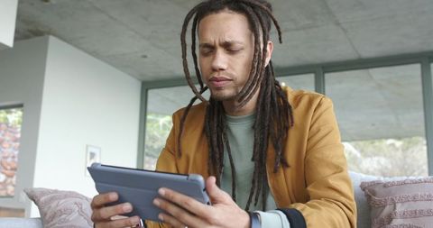 African american man using tablet on sofa in modern minimalist living room
