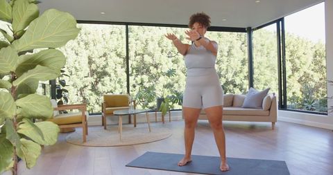 Woman exercising with squats on yoga mat at home