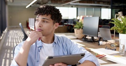 Contemplative office professional holding tablet in modern workspace