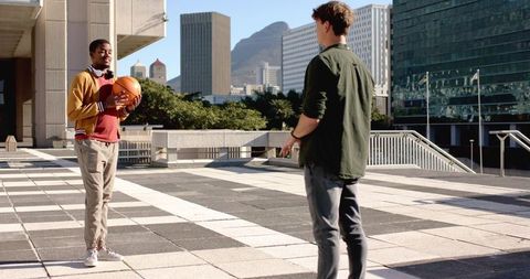 Passing Basketball on City Plaza while Friends Chatting with Headphones and Phone