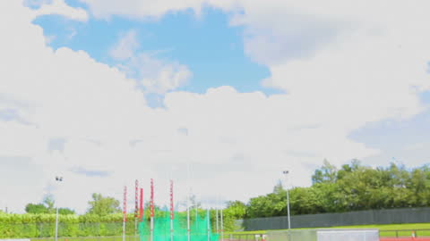 Brunette Athlete Throwing Javelin in Sunny Stadium