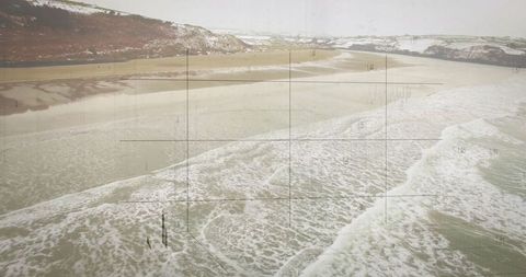 Snow-covered hills overlooking waves on sandy coastline