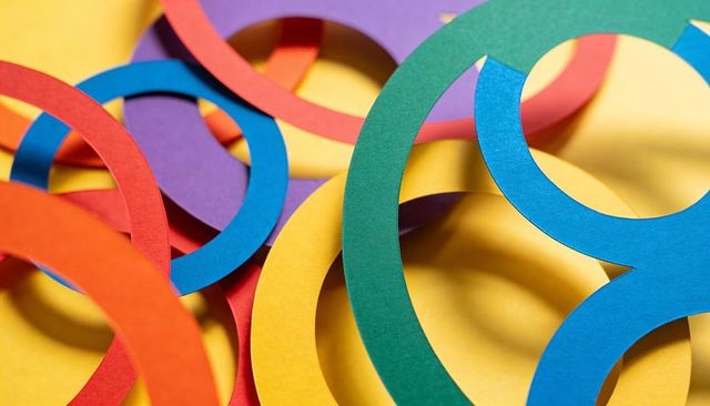 Overlapping colorful paper rings casting soft shadows on yellow background for craft design
