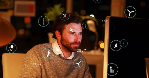 Caucasian Businessman Analyzing Eco Icons on Laptop at Night