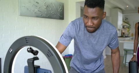 Couple preparing ring light and smartphone for livestream in bright home kitchen