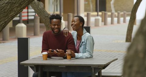 Couple Relaxing Outdoors Sharing Smartphone Moments