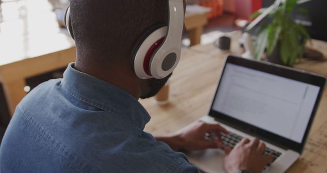 Man Wearing Headphones Working on Laptop at Wooden Desk - Download Free Stock Images Pikwizard.com