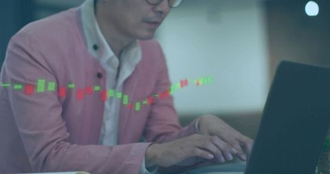 Asian man typing on laptop with candlestick chart overlay for trading and investments