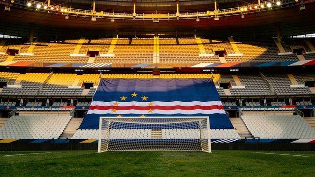 Cape verde flag draping behind goal on sunlit empty stadium pitch for football event