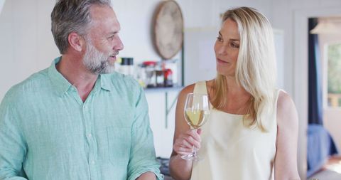 Happy Mature Couple Cooking and Drinking Wine in Kitchen