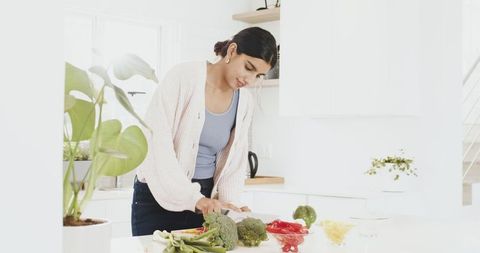 Woman prepares fresh vegetables in bright modern kitchen