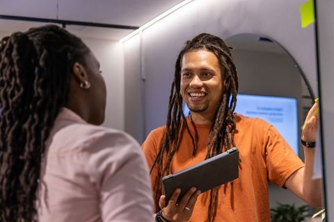 African american coworkers presenting with tablet and sticky notes in modern office