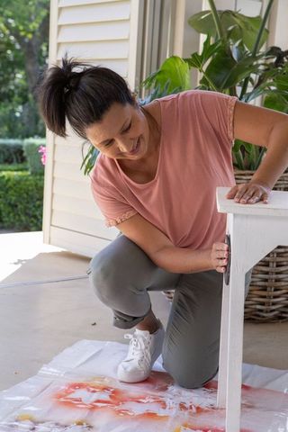 Senior woman sanding table on porch for diy home project