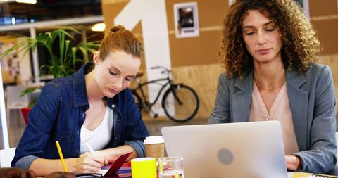 Two Professional Women Collaborating in Modern Office Environment