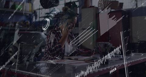Female entrepreneur talking on phone while reviewing documents at creative studio desk