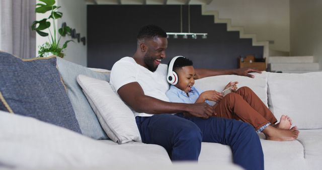 Father and Son Enjoying Leisure Time on Sofa with Digital Device - Download Free Stock Images Pikwizard.com