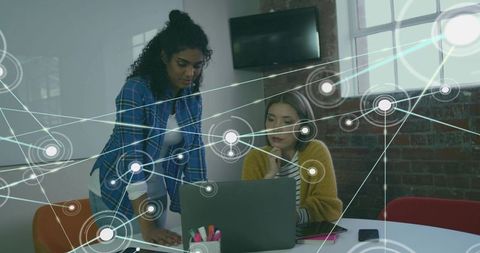 Women Collaborating Over Laptop in Modern Office Showing Digital Network Overlay