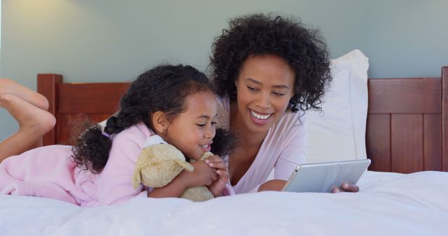 Mother and Daughter Reading from Digital Tablet While Relaxing on Bed - Download Free Stock Images Pikwizard.com