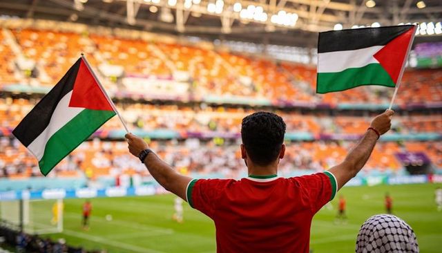 Football fan waving palestinian flags in stadium celebrating team support and unity