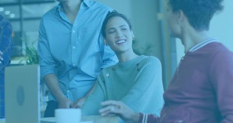 Smiling Hispanic Woman Engaging Colleagues at Work Desk